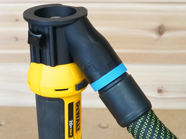 Black hose adapter attached to yellow Dewalt drywall cut out tool, with blue tape and green-patterned hose connected below