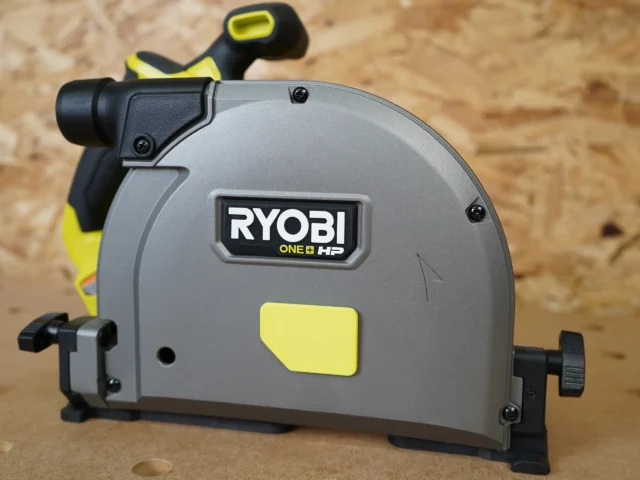 Black and yellow dust cover attached to a Ryobi ONE+ HP track saw, with snap-on design visible on the arbor housing