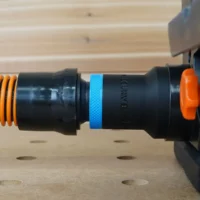 Black 1-1/4 inch hose adapter with blue grip ring joining an orange vacuum hose to a Wen sander dust port