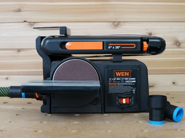 ToolCurve hose adapter attached to dust port of Wen belt and disc sander, with blue and black cylindrical connector visible