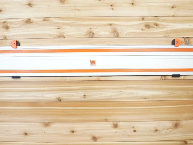 Wen track saw rail mounted on wooden wall with orange end caps and black locking handles on both sides