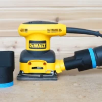 Black ToolCurve 36mm hose adapter with blue band beside a DeWalt palm sander connected to an extractor hose