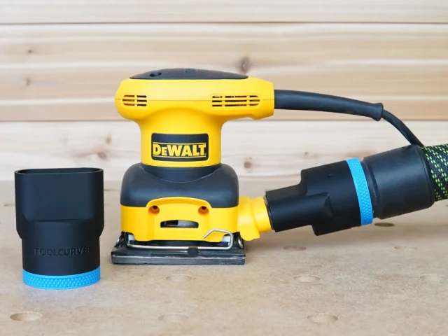 Black ToolCurve 36mm hose adapter with blue band beside a DeWalt palm sander connected to an extractor hose