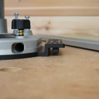 Guide rail adapter for Dewalt 2-1/4 HP router mounted on aluminum track, showing black knob adjustment and round dust port