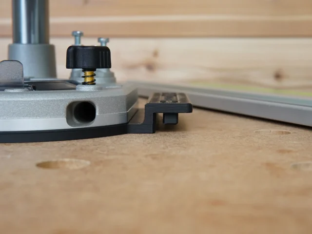 Guide rail adapter for Dewalt 2-1/4 HP router mounted on aluminum track, showing black knob adjustment and round dust port