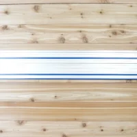 Two blue wall mounts holding a Kreg ACS track saw rail horizontally on wooden wall studs