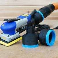 Two black ToolCurve 2-1/2 inch hose adapters with blue ribbed collars beside a blue Ekasand sander and hose