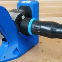Black 2-1/2 inch hose adapter with blue collar joining a vacuum hose to a blue Kreg 720 pocket-hole jig