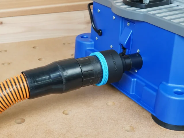 Black ToolCurve 2-1/2 inch hose adapter with blue collar linking an orange hose to the Kreg Foreman rear dust port