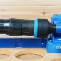 Black ToolCurve 2-1/2 inch hose adapter with blue band joining an orange hose to a blue Kreg K5 jig dust port