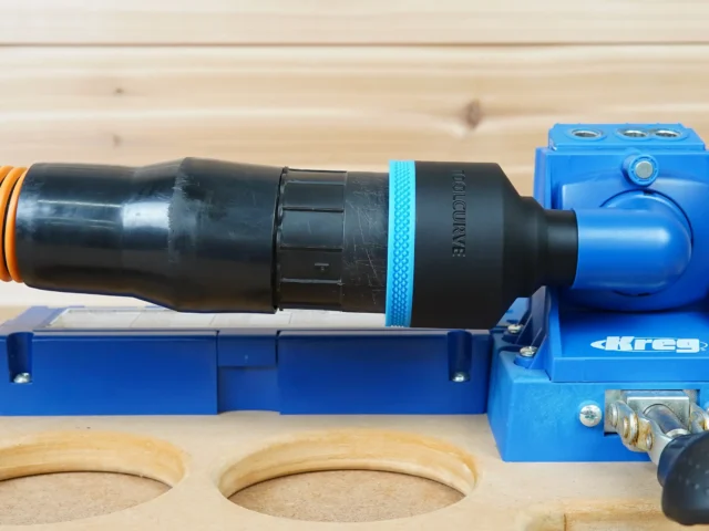 Black ToolCurve 2-1/2 inch hose adapter with blue band joining an orange hose to a blue Kreg K5 jig dust port