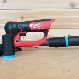 Black ToolCurve hose adapter with blue band joining a vacuum hose to a Milwaukee M12 Fuel detail sander, spare adapter alongside