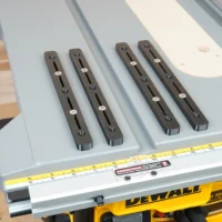 Set of 4 black miter bars with lengthwise slots and countersink holes, arranged on a DeWalt table saw fence