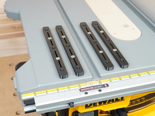 Set of 4 black miter bars with lengthwise slots and countersink holes, arranged on a DeWalt table saw fence