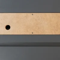 Tan MDF zero clearance insert with single center hole, mounted on dark gray SawStop table saw with four corner screws visible