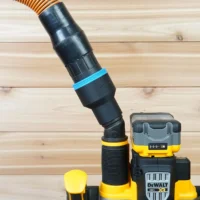 Black ToolCurve 2-1/2 inch hose adapter with blue band linking an orange vacuum hose to a DeWalt cordless plunge router dust port
