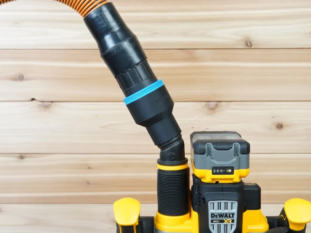 Black ToolCurve 2-1/2 inch hose adapter with blue band linking an orange vacuum hose to a DeWalt cordless plunge router dust port