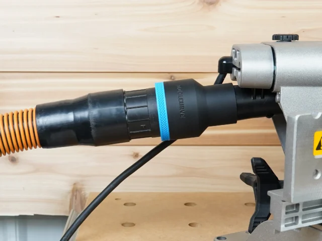 Black ToolCurve 2-1/2 inch hose adapter with blue band joining an orange vac hose to a DeWalt miter saw dust port