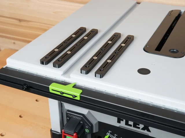 Four brown adjustable miter bars with countersink holes mounted on a Flex table saw, with a lime-green clamp positioned on the front rail