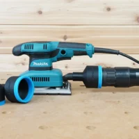 Black and blue ToolCurve 2-1/2 inch hose adapter connecting an orange extractor hose to a Makita sander, with a second adapter beside it