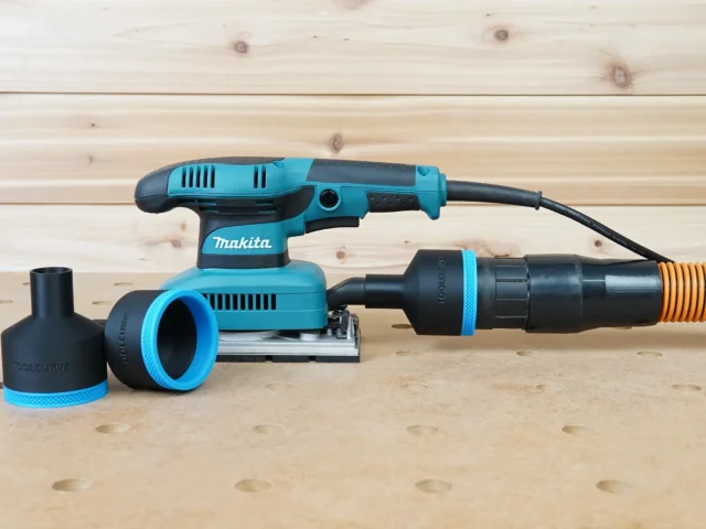 Black and blue ToolCurve 2-1/2 inch hose adapter connecting an orange extractor hose to a Makita sander, with a second adapter beside it