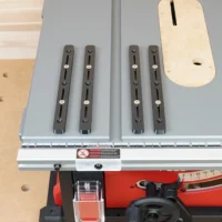 Four black adjustable miter bars mounted on a Milwaukee table saw fence, with a natural wood template above showing mounting hole positions