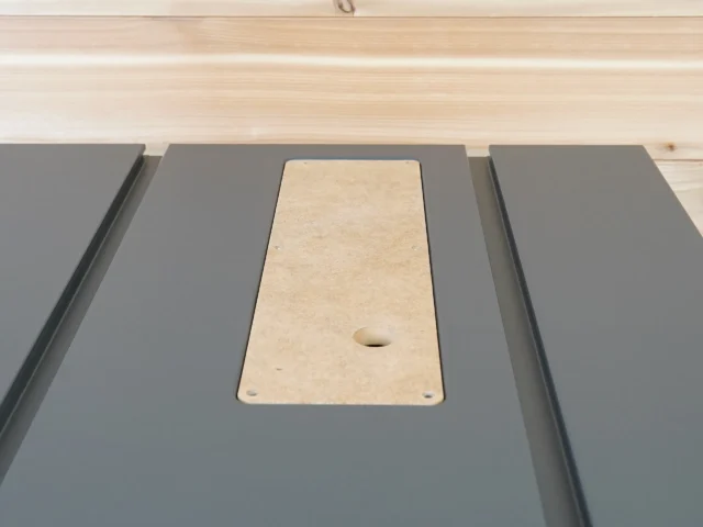 Natural MDF zero clearance insert seated in gray SawStop Compact table saw with central blade opening and mounting holes visible