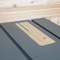 Light wood zero clearance insert with center slot and mounting hole, positioned on dark gray table saw inserts