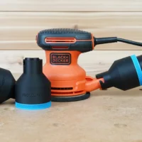 Two black ToolCurve 2-1/2 inch hose adapters with blue trim beside a Black and Decker orange sander and hose