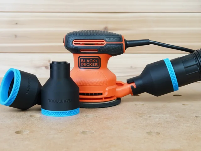 Two black ToolCurve 2-1/2 inch hose adapters with blue trim beside a Black and Decker orange sander and hose
