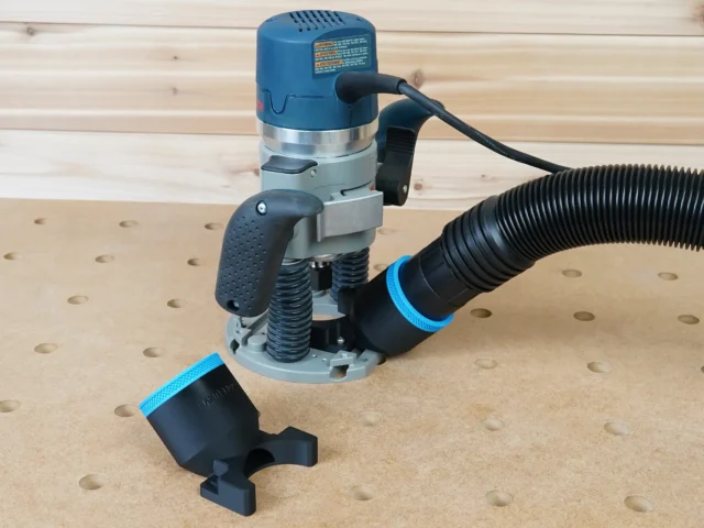 Black 2-1/2 inch hose adapter with blue collar on Bosch 1617 plunge router, second adapter on the bench