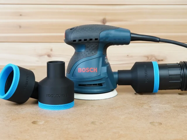 Black ToolCurve 2-1/2" hose adapters with blue trim beside a Bosch 5in sander, one joined to a vac hose