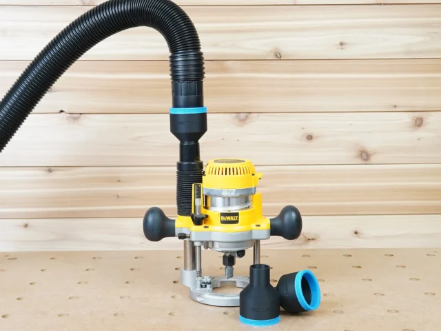 Black 2-1/2 inch hose adapter with blue band joining an extractor hose to a Dewalt plunge router, two spares nearby