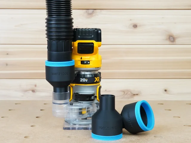 Black 2-1/2" hose adapter with blue trim on a Dewalt trim router, plus two loose adapters on the bench