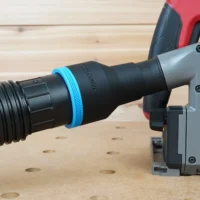 Black ToolCurve 2-1/2 inch hose adapter with blue ring joining a ribbed vacuum hose to a Milwaukee track saw dust port