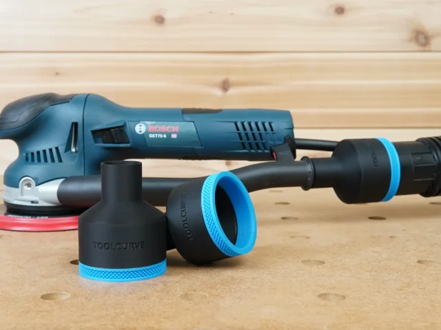 Two black ToolCurve 2-1/2 inch hose adapters with blue ribbed collars in front of a Bosch GET75-6 sander