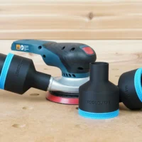 Black ToolCurve 2-1/2" hose adapter with blue trim on a Bosch GEX sander, two spare adapters alongside