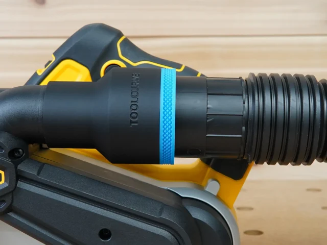 Black ToolCurve 2-1/2 inch hose adapter with blue band installed on a Dewalt 20v belt sander dust port with hose attached