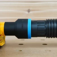 Black ToolCurve 2-1/2 inch hose adapter with blue ring joining a ribbed vacuum hose to a yellow Dewalt planer dust port