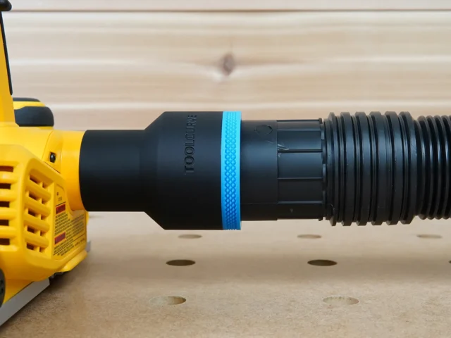 Black ToolCurve 2-1/2 inch hose adapter with blue ring joining a ribbed vacuum hose to a yellow Dewalt planer dust port