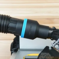 Black 2-1/2 inch ToolCurve hose adapter with blue ring joining a vacuum hose to a DeWalt table saw blade guard port