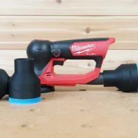 Black ToolCurve 2-1/2 inch hose adapter with blue trim beside a Milwaukee M12 detail sander, second piece on a hose