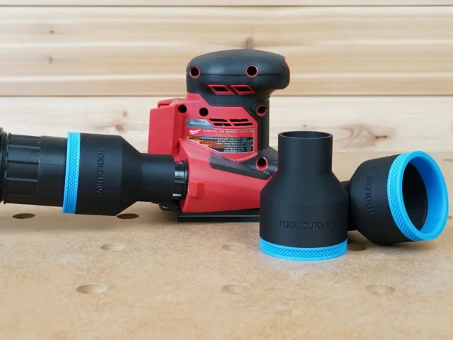 Black 2-1/2 inch hose adapter with blue trim connecting a vacuum hose to a Milwaukee 18v sheet sander, plus spare