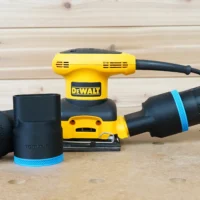 Black ToolCurve 2-1/2 inch hose adapter with blue trim shown alone and installed on a DeWalt palm sander