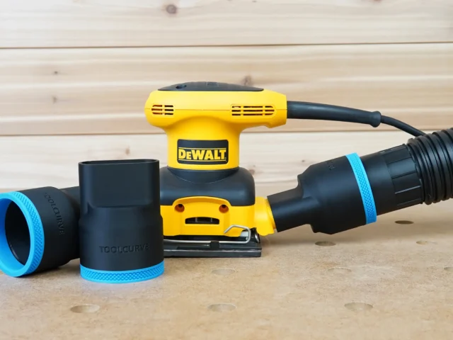 Black ToolCurve 2-1/2 inch hose adapter with blue trim shown alone and installed on a DeWalt palm sander