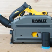 Black ToolCurve hose adapter with blue band joining a vacuum hose to a DeWalt track saw, two spare adapters beside it
