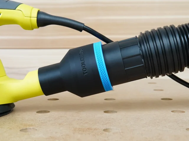 Black ToolCurve 2-1/2 inch hose adapter with blue ring joining a ribbed vacuum hose to a yellow Ryobi sander