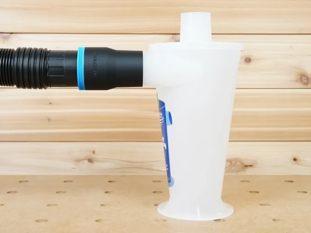 Black ToolCurve 2-1/2 inch hose adapter with blue ring joining a ribbed hose to a white Oneida Dust Deputy inlet