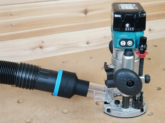 Black ToolCurve 2-1/2 inch hose adapter with blue band linking a vacuum hose to a Makita plunge router dust port
