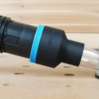 Black ToolCurve 2-1/2 inch hose adapter with blue ring joining a vacuum hose to a Makita trim router dust port